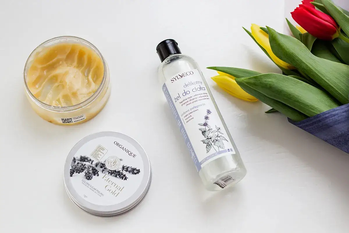 Kosmetyki do pielęgnacji ciała: peeling i żel pod prysznic, obok bukiet tulipanów. Inspiracja botanicapharma dla Twojej skóry.