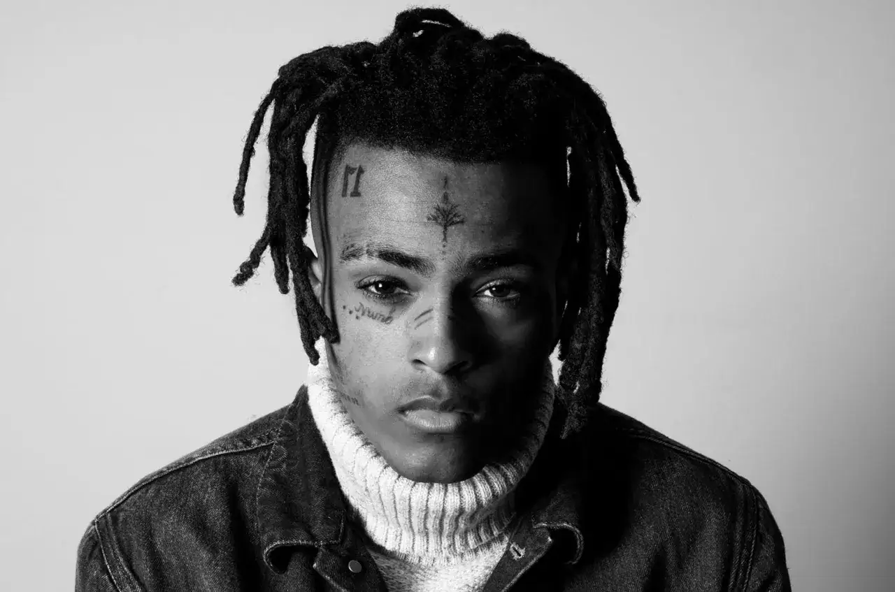 XXXTentacion, w czarno-białym portrecie, z tatuażami na twarzy i dredami. Kto zabił XXXTentaciona? Pytanie wciąż bez odpowiedzi.