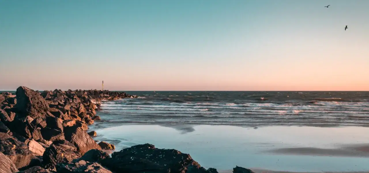 Kamienista plaża i morze o zachodzie słońca. Woda morska jest bogata w jod, a wybrzeża Europy, jak to, są idealnym miejscem, by poczuć jego dobroczynny wpływ.
