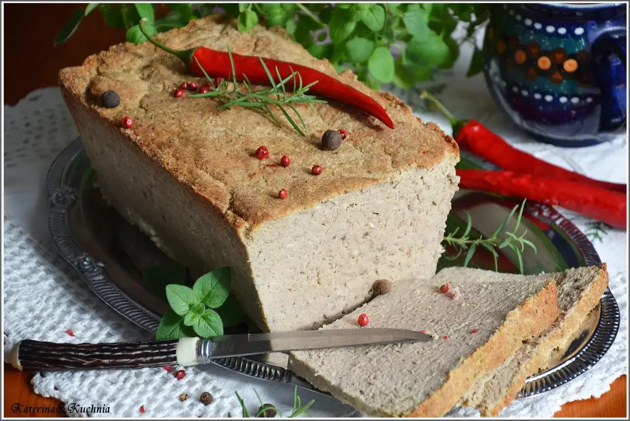 Domowy pasztet drobiowo-wieprzowy z wątróbką, udekorowany papryczką chili i rozmarynem, gotowy do podania.