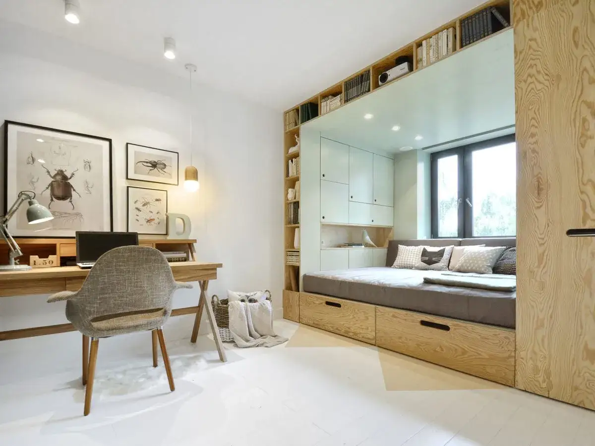 Acogedor dormitorio juvenil con cama empotrada, escritorio de madera y estanter&iacute;as llenas de libros.