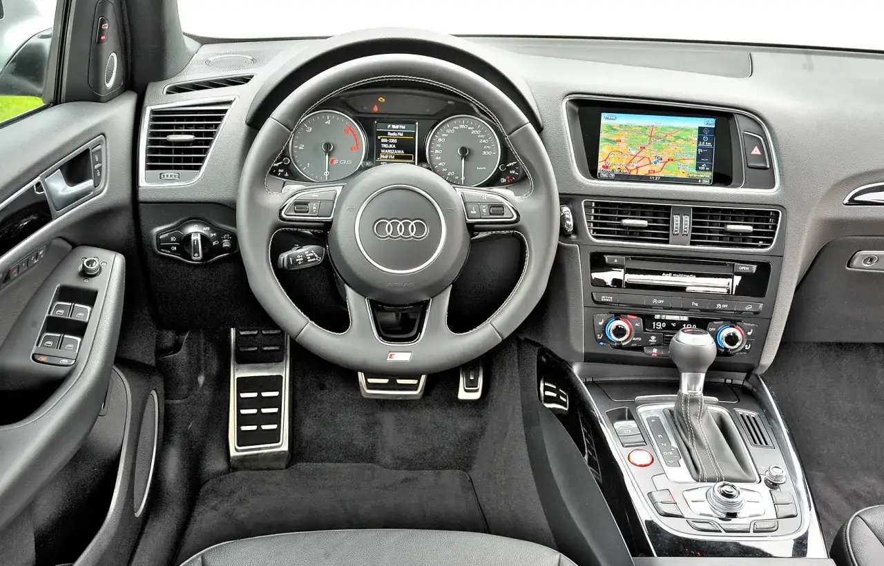 Wnętrze Audi z nawigacją i sportową kierownicą. Zastanawiasz się, które audi wybrać? Ten model oferuje komfort i nowoczesne technologie.