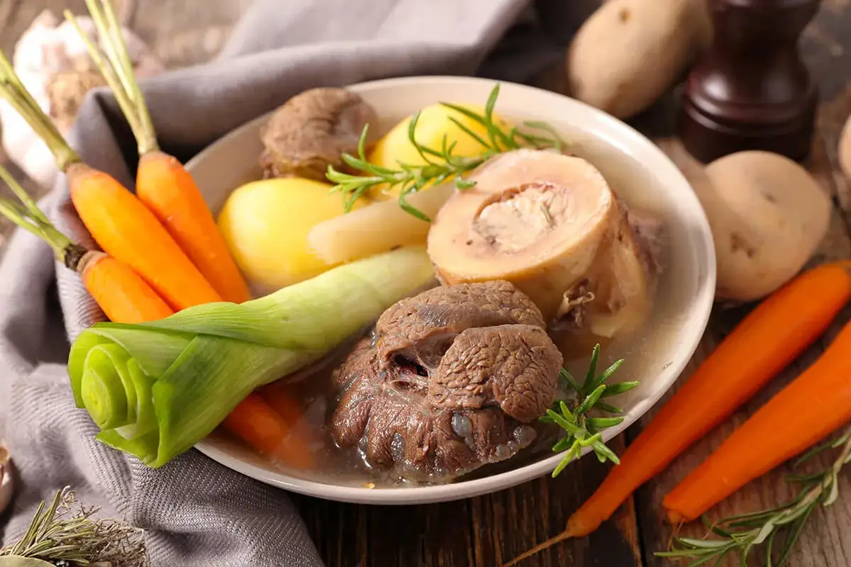 Un plat r&eacute;confortant de pot au feu, avec du b&oelig;uf, des carottes, des pommes de terre et des poireaux, garni de romarin.