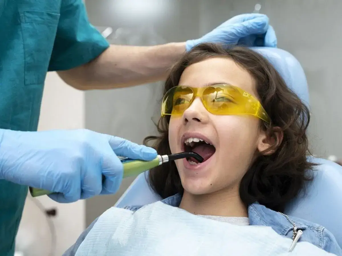 Dziecko z zębami rekina u dentysty. Specjalista w rękawiczkach bada jamę ustną.