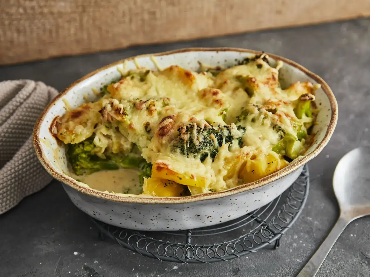 Herzhafter Kartoffel Zucchini Auflauf mit geschmolzenem Käse in einer Keramikform, bereit zum Servieren.