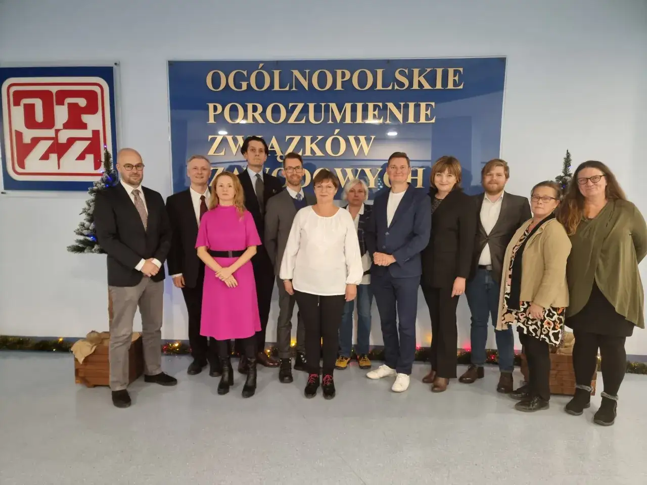 Grupa osób pozuje przed tablicą z napisem 
