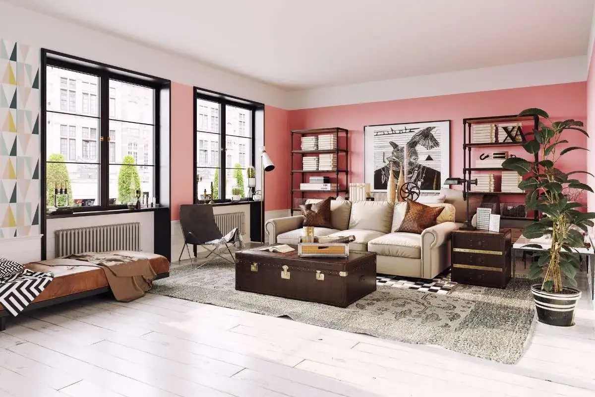 Gem&uuml;tliches Wohnzimmer mit rosa Wand, bequemer Couch, Vintage-Truhe und viel Licht durch gro&szlig;e Fenster.
