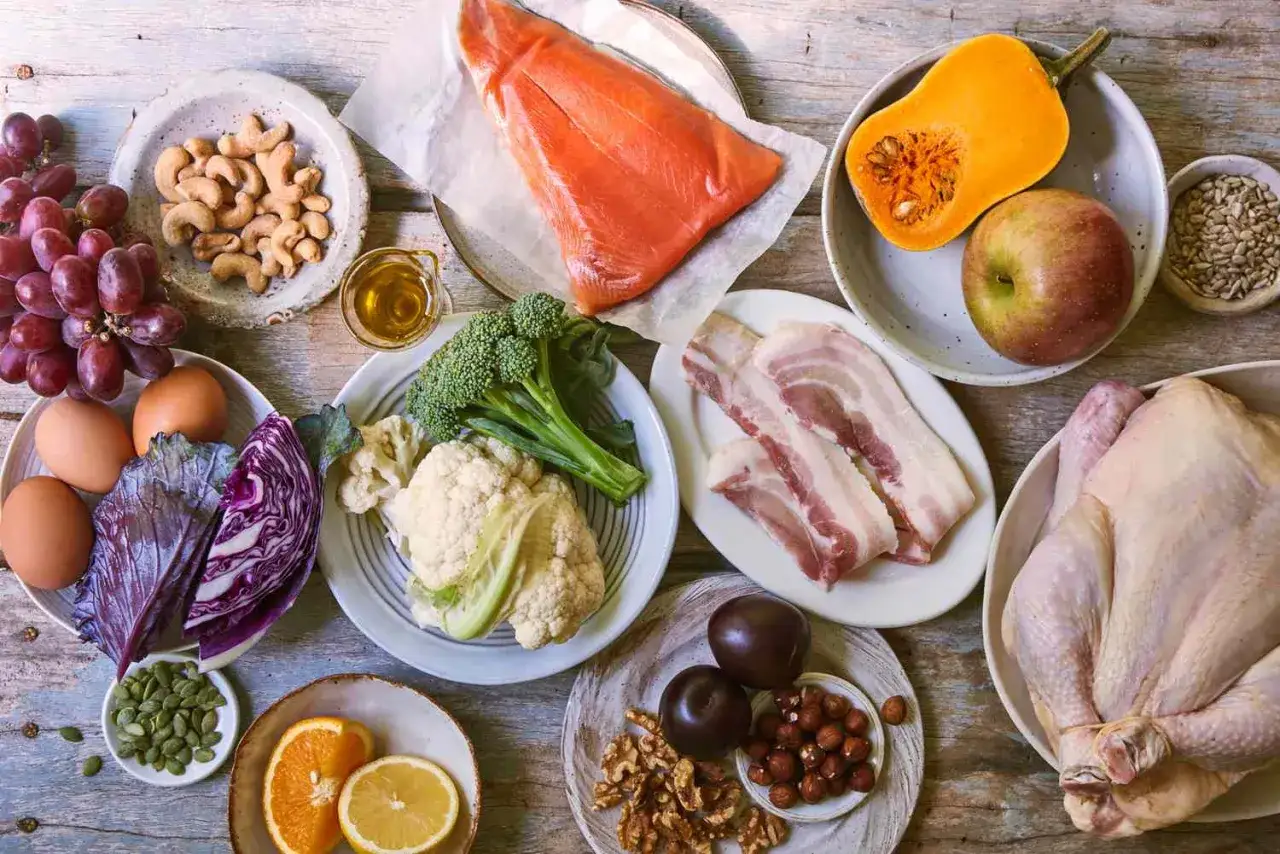 Ingredienti per una dieta paleo: salmone, pollo, uova, verdure, frutta, noci e semi.