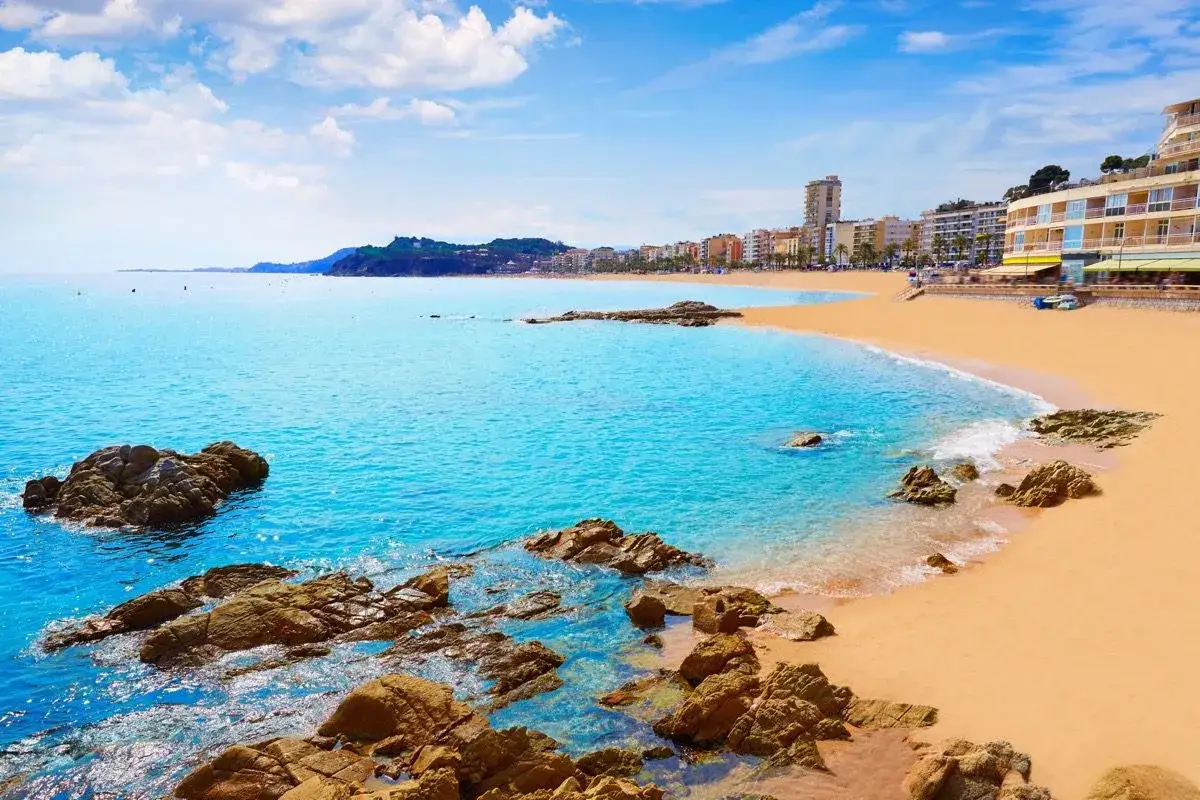 Piękna plaża w Lloret de Mar w czerwcu. Słoneczna pogoda, turkusowe morze i złoty piasek zapraszają na wakacje.