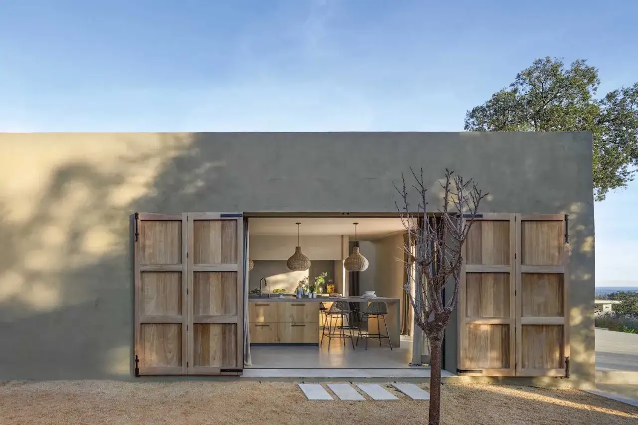 Fachadas de casas modernas con puertas de madera corredizas que revelan una cocina luminosa y acogedora.