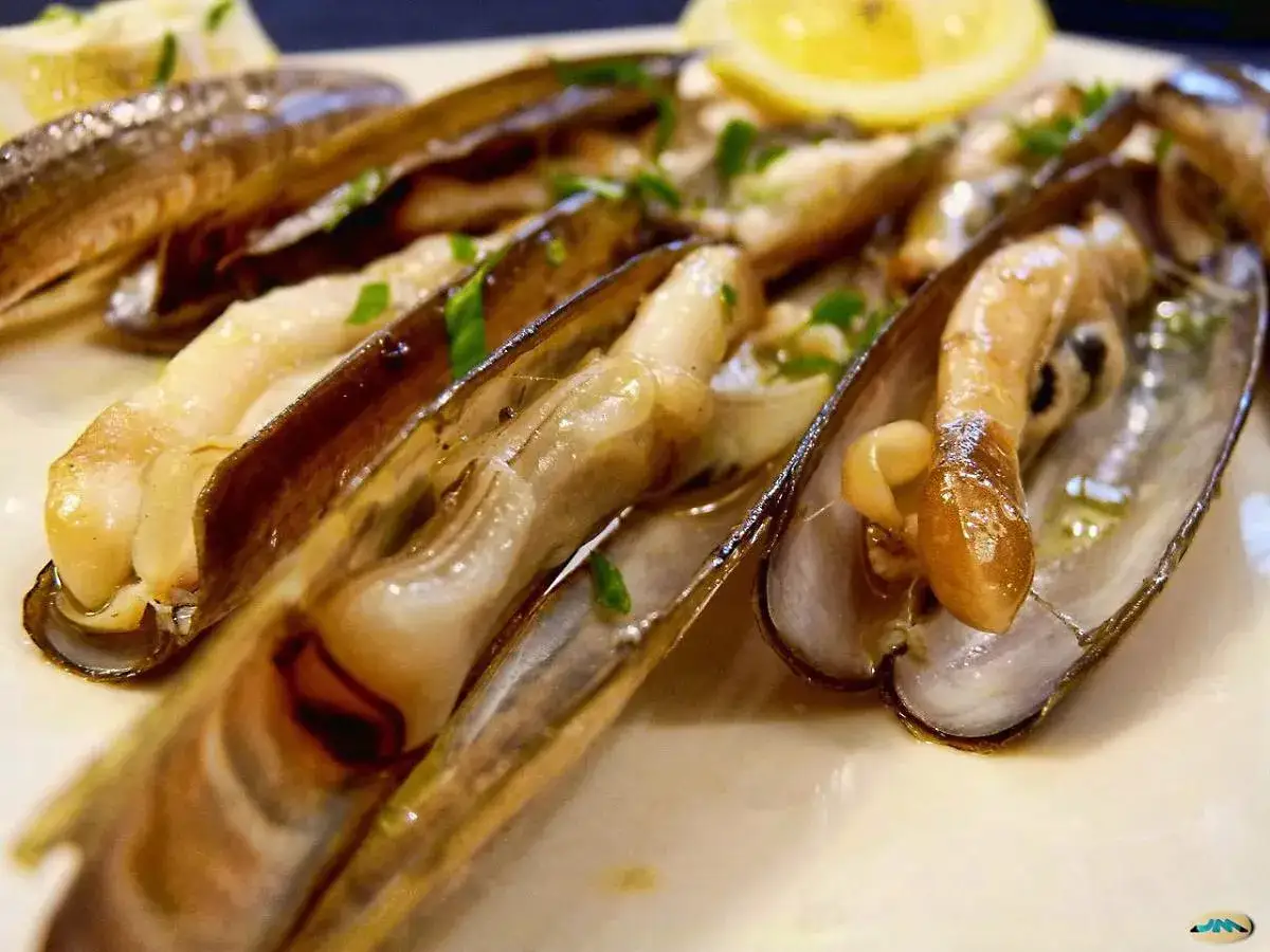 Navajas cocinadas en su jugo, con perejil picado y una rodaja de limón. Se pueden congelar para disfrutar más tarde.