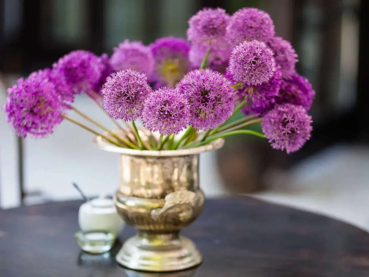 Un bouquet d'alliums violets dans un vase argenté. Pour savoir comment conserver des fleurs coupées, il faut penser à l'eau fraîche et à la lumière indirecte.