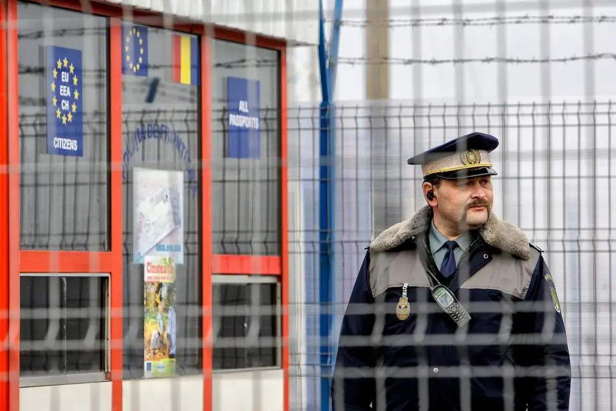 Strażnik graniczny w mundurze przy budce z flagami UE i Rumunii. Wkrótce Rumunia w strefie Schengen.