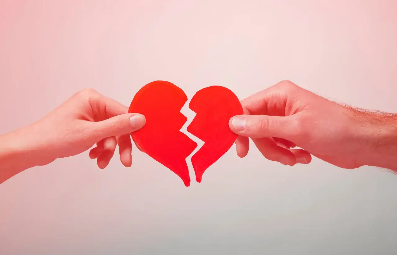 Dos manos separan un coraz&oacute;n rojo roto, un s&iacute;mbolo de que el amor puede hacerte morir de amor.