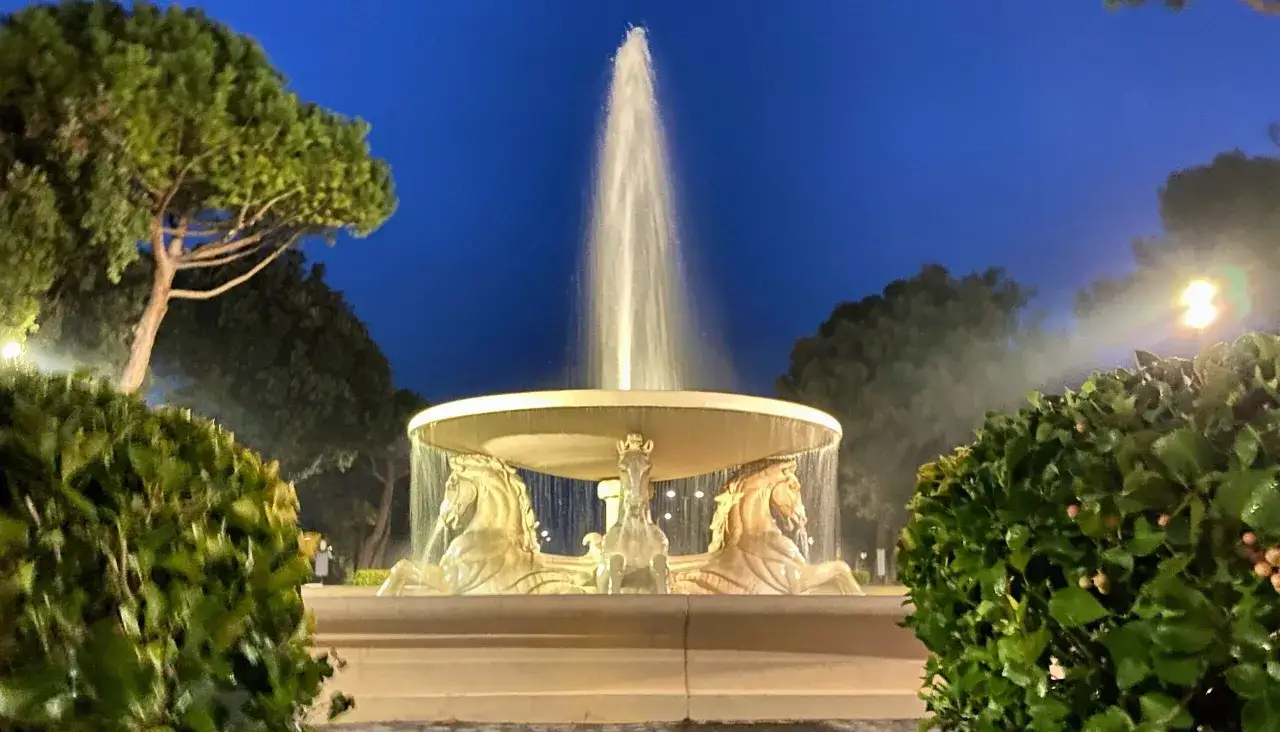 Fontana con cavalli marini nel Parco Fellini di Rimini, illuminata di notte.