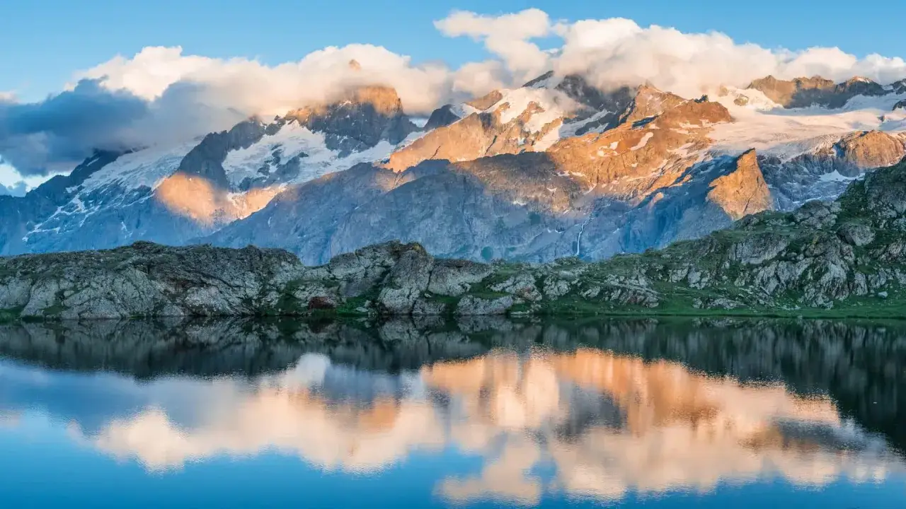 Reflets d'un lac alpin sur des montagnes enneig&eacute;es au lever du soleil. Parfait pour une randonn&eacute;e Alpes 3 jours.