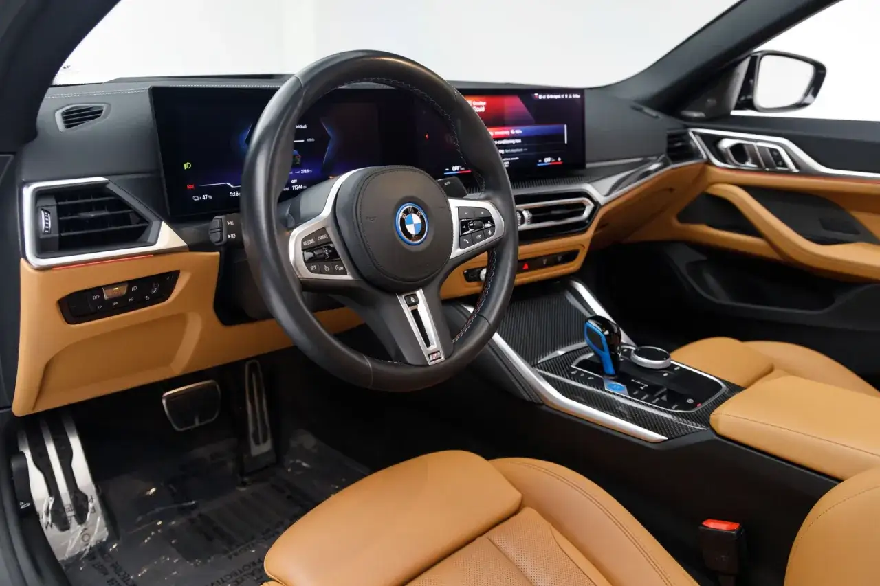 Wnętrze BMW E4 z brązową skórzaną tapicerką, nowoczesnym kokpitem i cyfrowymi ekranami.