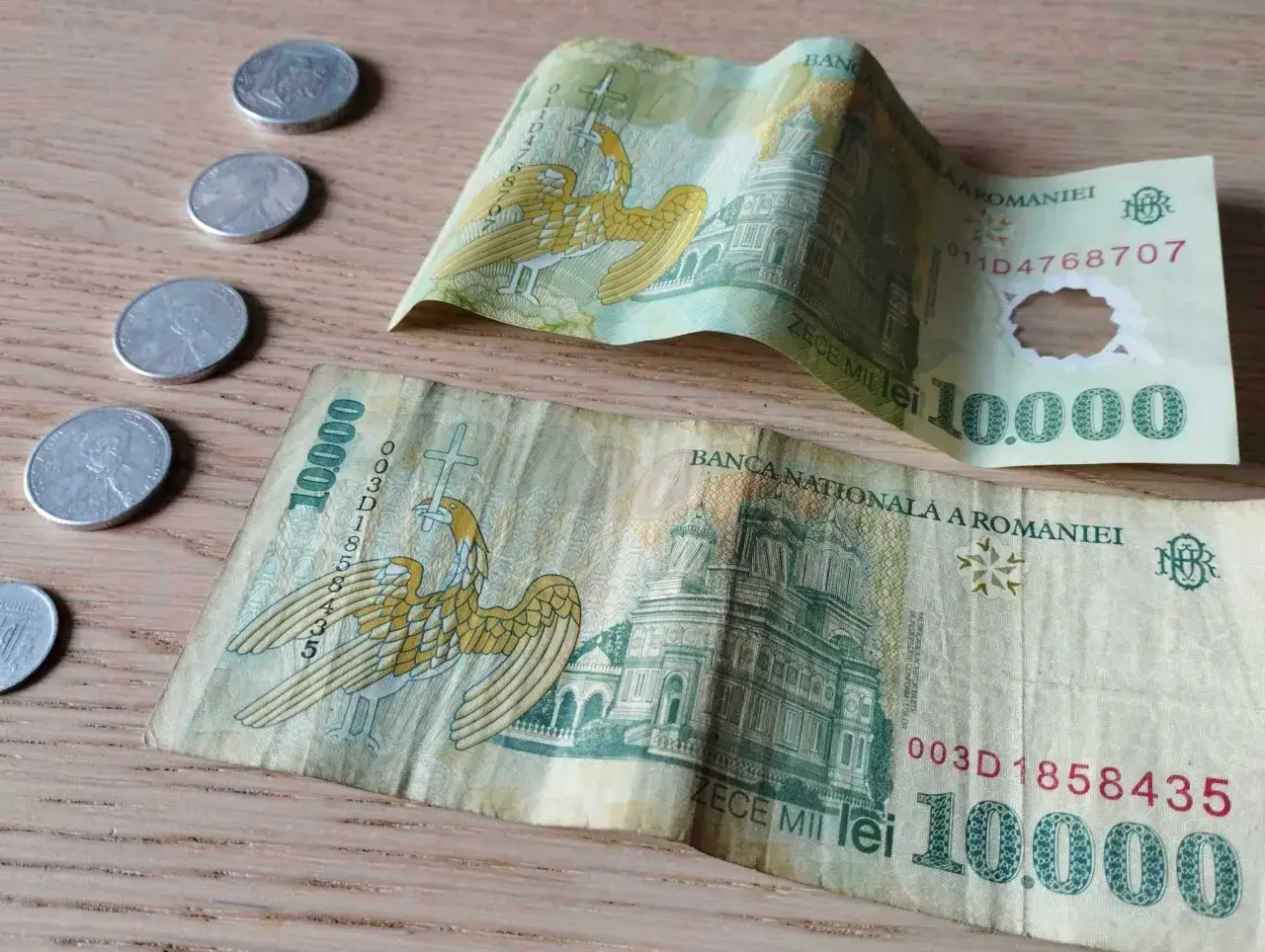Dwie banknoty 10 000 lei i kilka monet. Rumunia waluta, lei, na drewnianym tle.