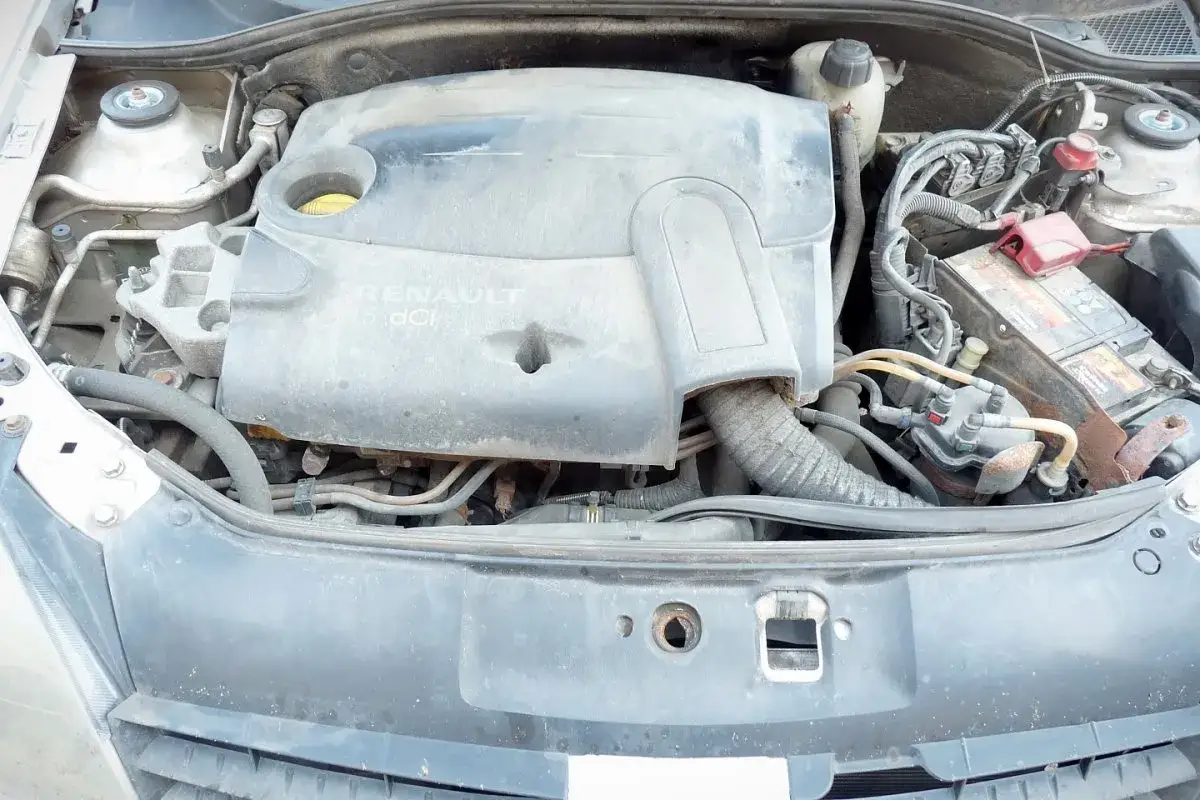 Silnik Renault 1.5 dCi pod maską samochodu, widoczna pokrywa silnika, akumulator i przewody.