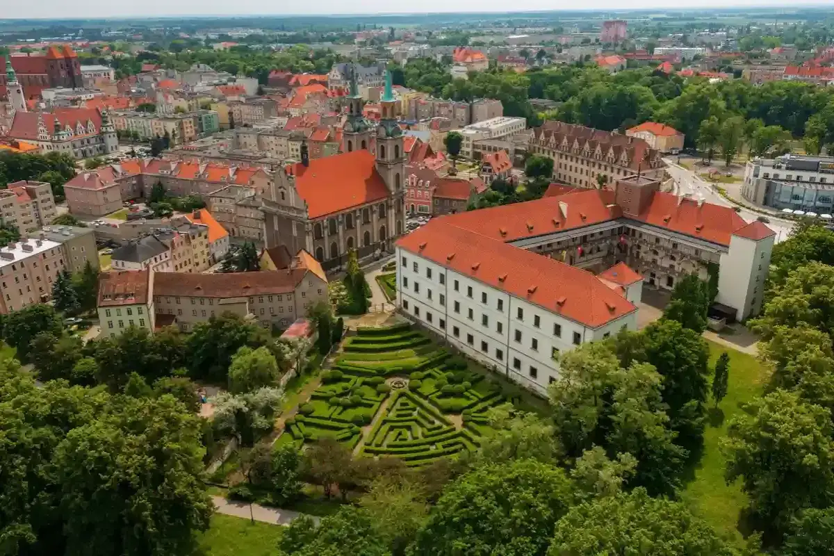 Widok z lotu ptaka na zamek i ogr&oacute;d w stylu francuskim, z dominującą architekturą miasta na brzeg opolski.