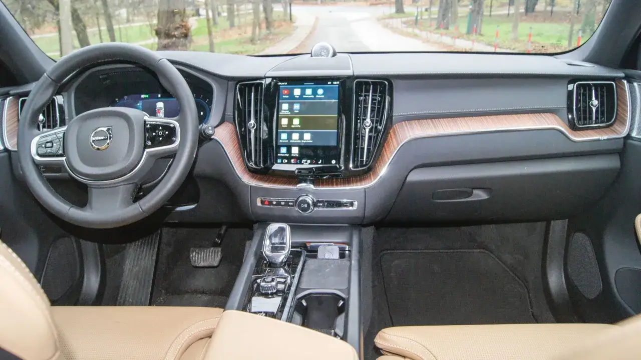 Wnętrze Volvo XC60 z ekranem dotykowym i drewnianymi wstawkami. Kierowca zastanawia się, ile pali to auto.