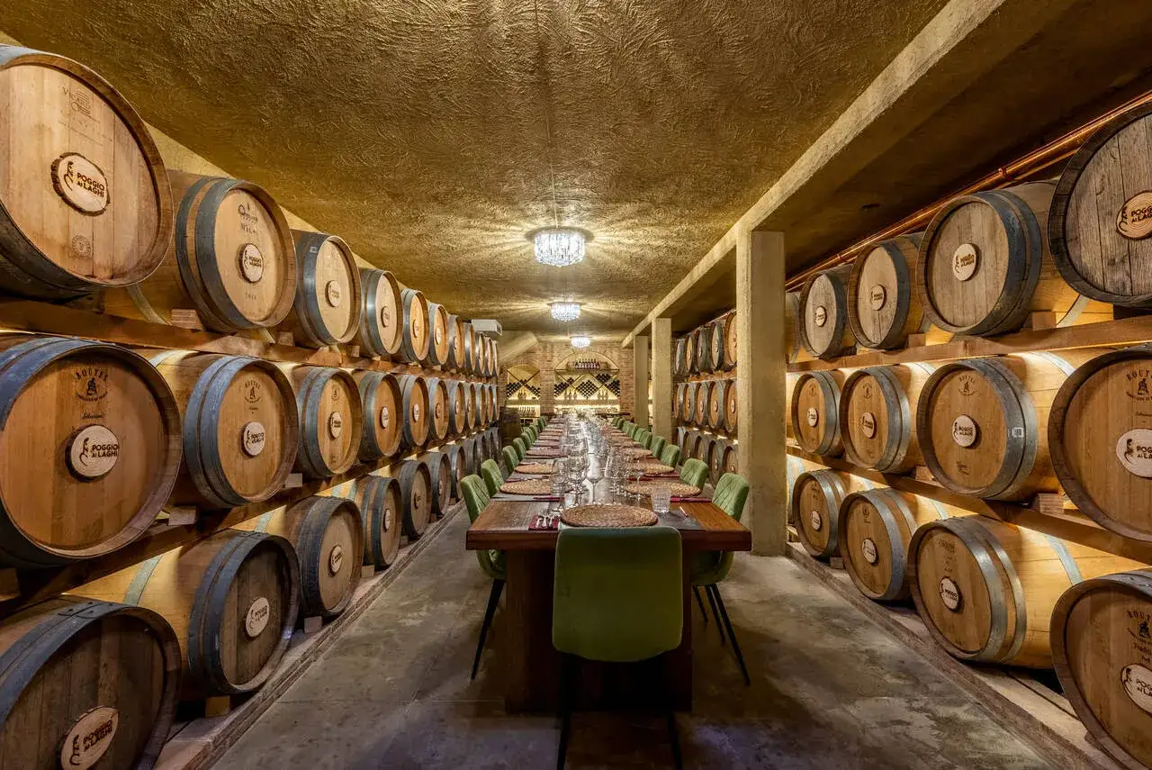 Cantine a Firenze: lunga tavola apparecchiata tra botti di legno, ideale per un'esperienza enogastronomica.