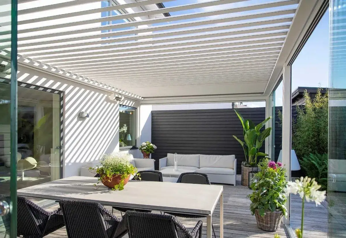 En modern uteplats med ett stilrent tak som ger skugga. Här kan du njuta av sommaren, perfekt för att bygga pergola med tak.