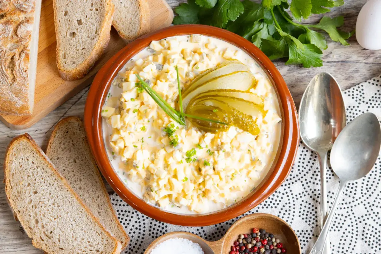 Ein cremiger Eiersalat, garniert mit Gurkenscheiben und Schnittlauch, bereit zum Servieren mit frischem Brot. Ein einfaches eiersalat rezept.