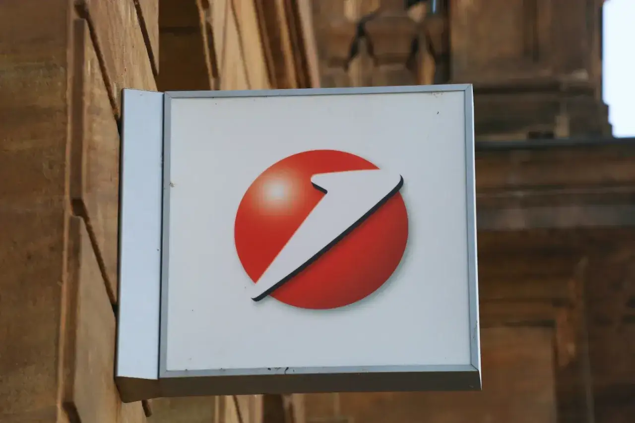 Znak Aion Bank z czerwoną kulą i białym strzałką.