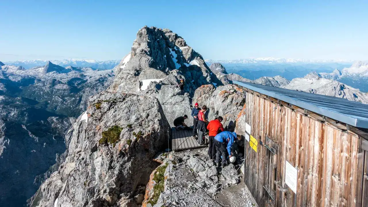 Bergsteiger am Watzmannhaus nach einer anstrengenden Watzmannhaus Wanderung. Die H&uuml;tte thront auf einem Felsvorsprung mit Blick auf die Alpen.