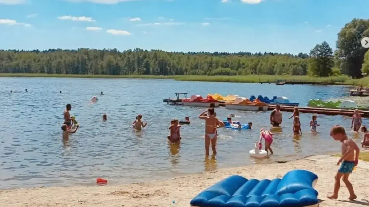 Rodzina cieszy się lipcowym słońcem i kąpielą w jeziorze. Idealne miejsce, gdzie na wakacje w lipcu.