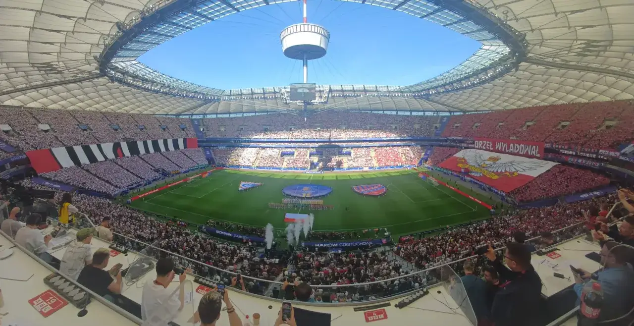 Stadion wypełniony kibicami na meczu Górnik Zabrze – Raków Częstochowa. Ogromna flaga z orłem na trybunach.