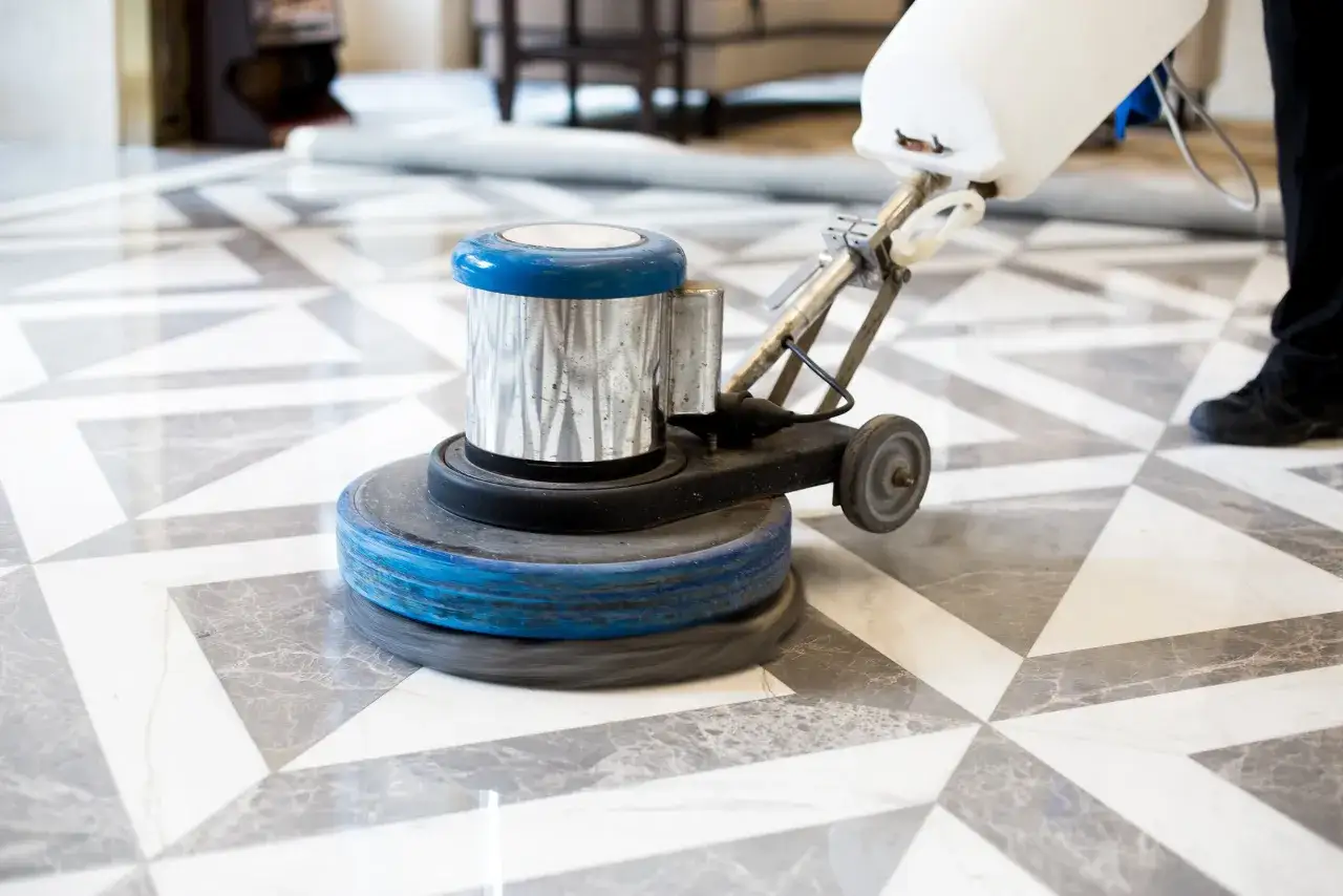 A floor buffer is used to clean marble floor tiles, restoring their shine.