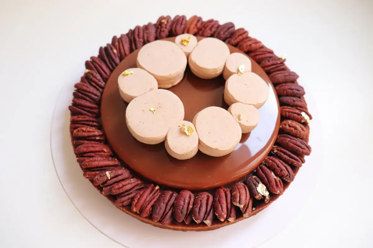 Tarte chocolat noix de pécan, décorée de petites meringues et de feuilles d'or. Un délice visuel et gustatif.