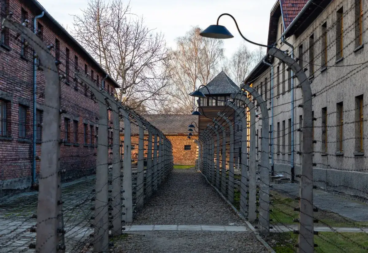 Droga przez Auschwitz, otoczona drutem kolczastym i budynkami, przypomina o historii. Zwiedzanie tego miejsca wymaga czasu, by zrozumieć jego wagę.
