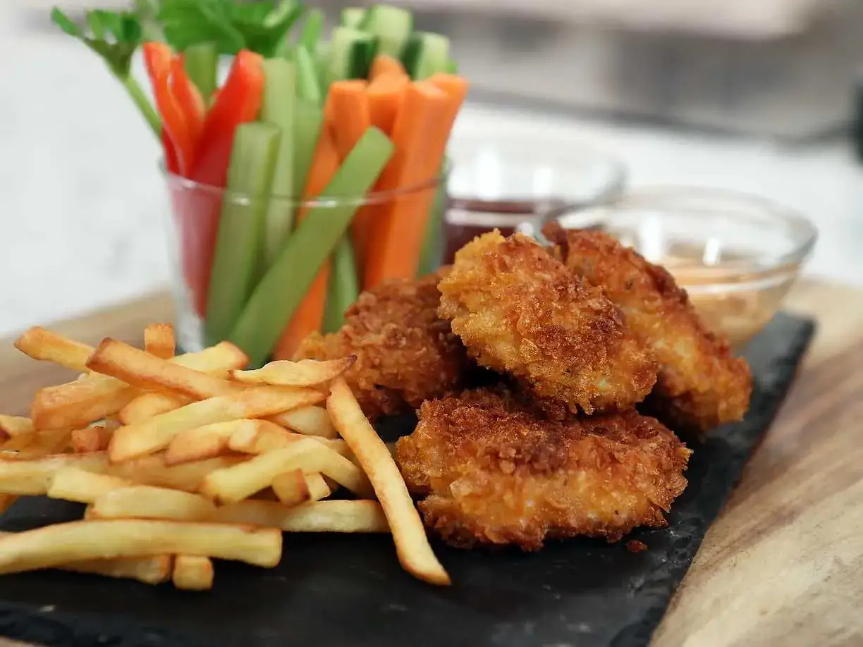 Krispiga chicken nuggets med pommes frites och gr&ouml;nsaksstavar. Perfekt f&ouml;r en snabb och god m&aring;ltid.