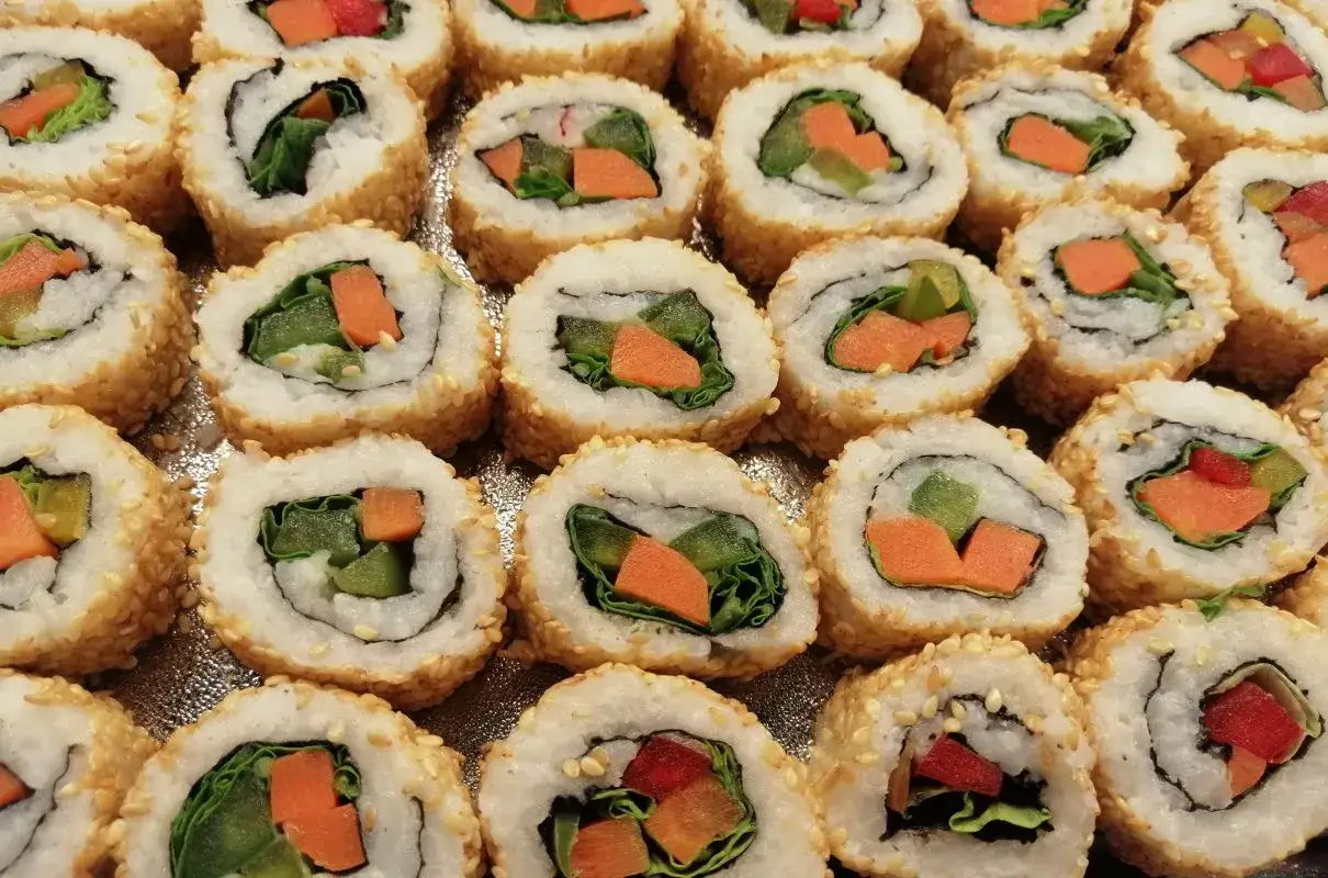 Roladki sushi z sezamem, w środku zielona sałata, marchewka i ogórek. Idealne warzywa do sushi na lekki posiłek.