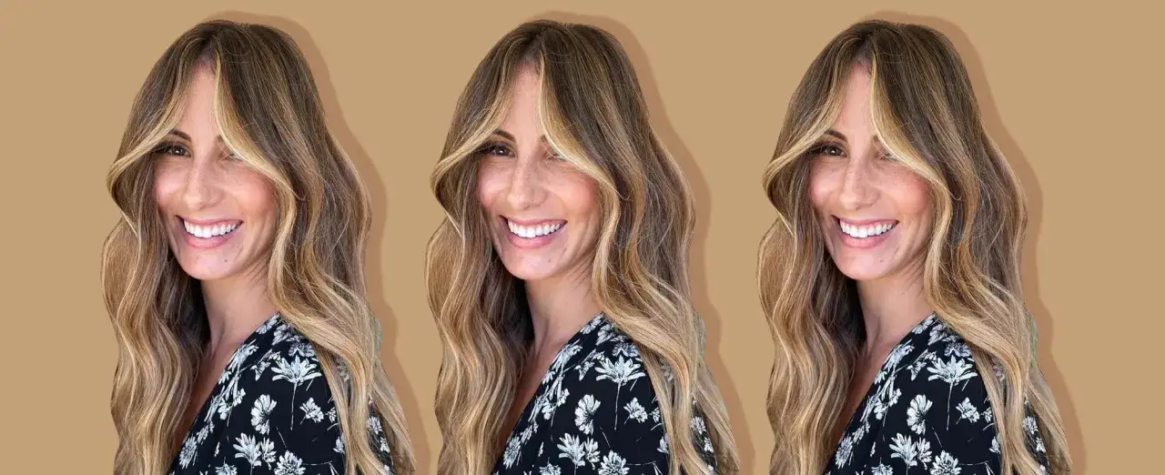 Mujer sonriente con cabello largo y ondulado, resaltado con mechas halo que iluminan su rostro.
