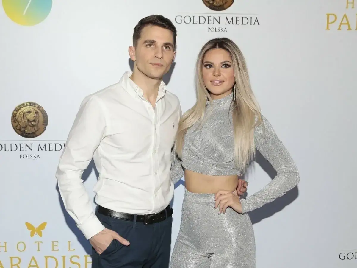 Para z Inga Hotel Paradise pozuje na ściance. Ona w srebrnym, błyszczącym komplecie, on w białej koszuli.