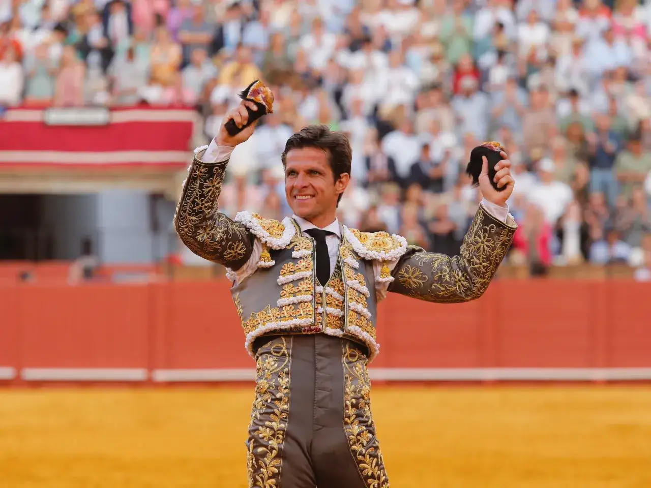 El Juli, sonriente y con las manos en alto, muestra trofeos ante un p&uacute;blico enardecido.