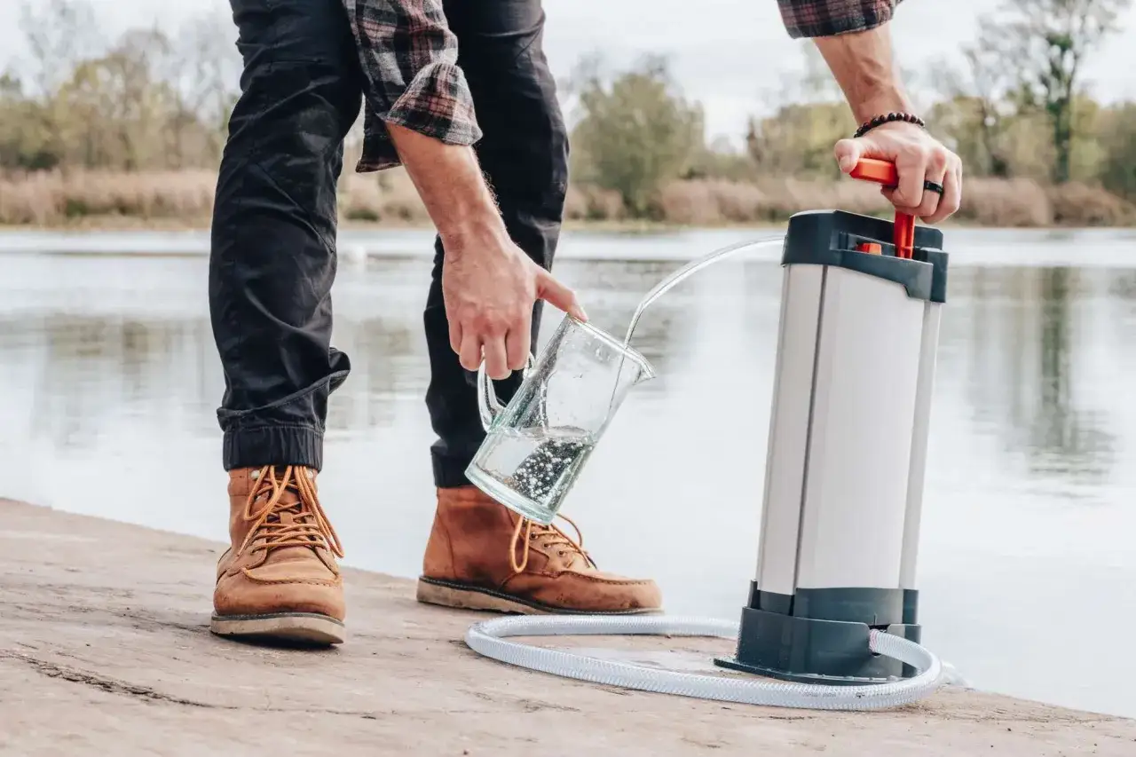 Un homme utilise un osmoseur portable près d'un lac pour purifier l'eau.