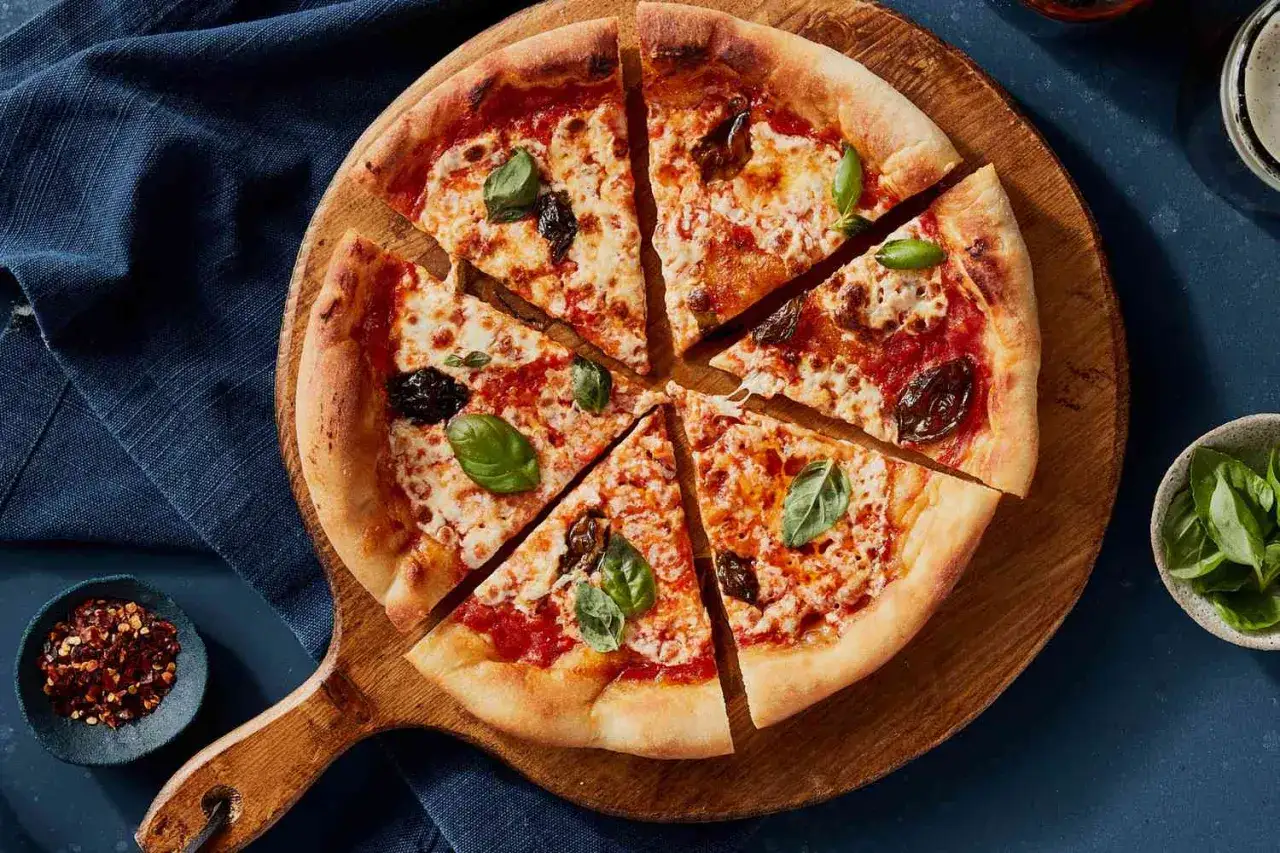 Une délicieuse margarita pizza, coupée en parts, garnie de basilic frais et de tomates. Parfait pour un repas savoureux.