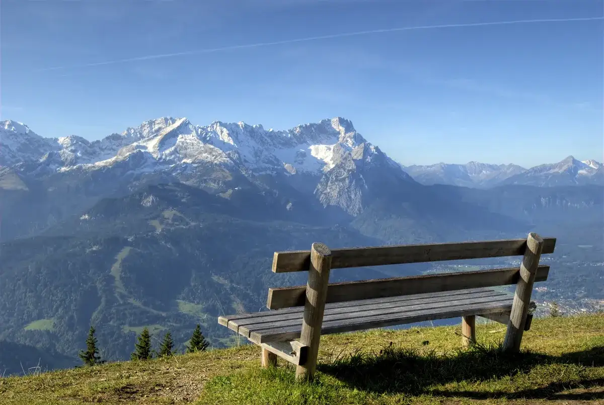 Holzbank mit Blick auf schneebedeckte Berge. Perfekt f&uuml;r eine Rast nach dem Wank wandern.
