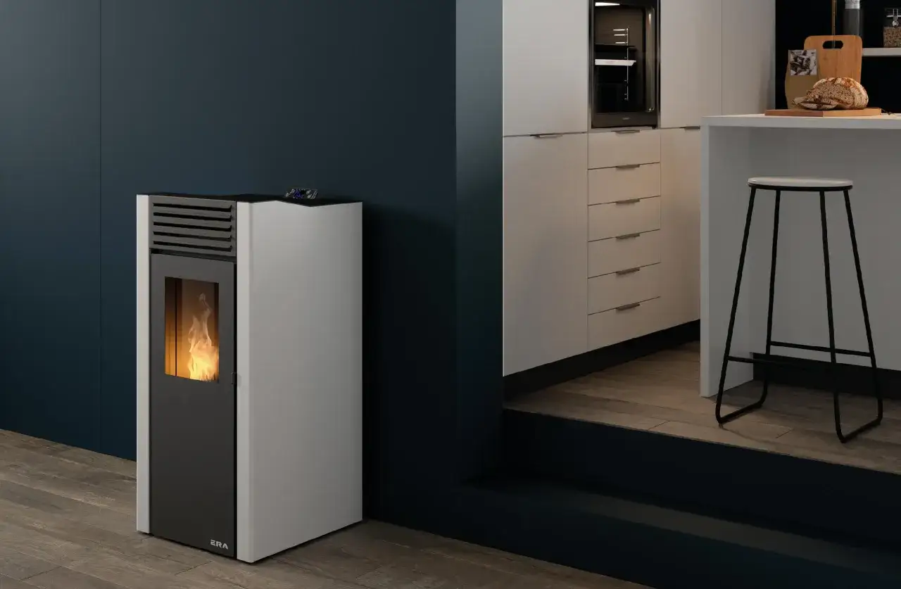 Estufa de pellet sin salida de humos con llama encendida, junto a una barra de cocina moderna con taburete.