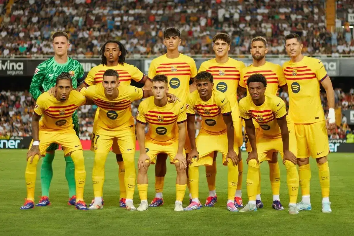 Drużyna FC Barcelona w żółtych strojach, z kapitanem na czele, gotowa do gry.
