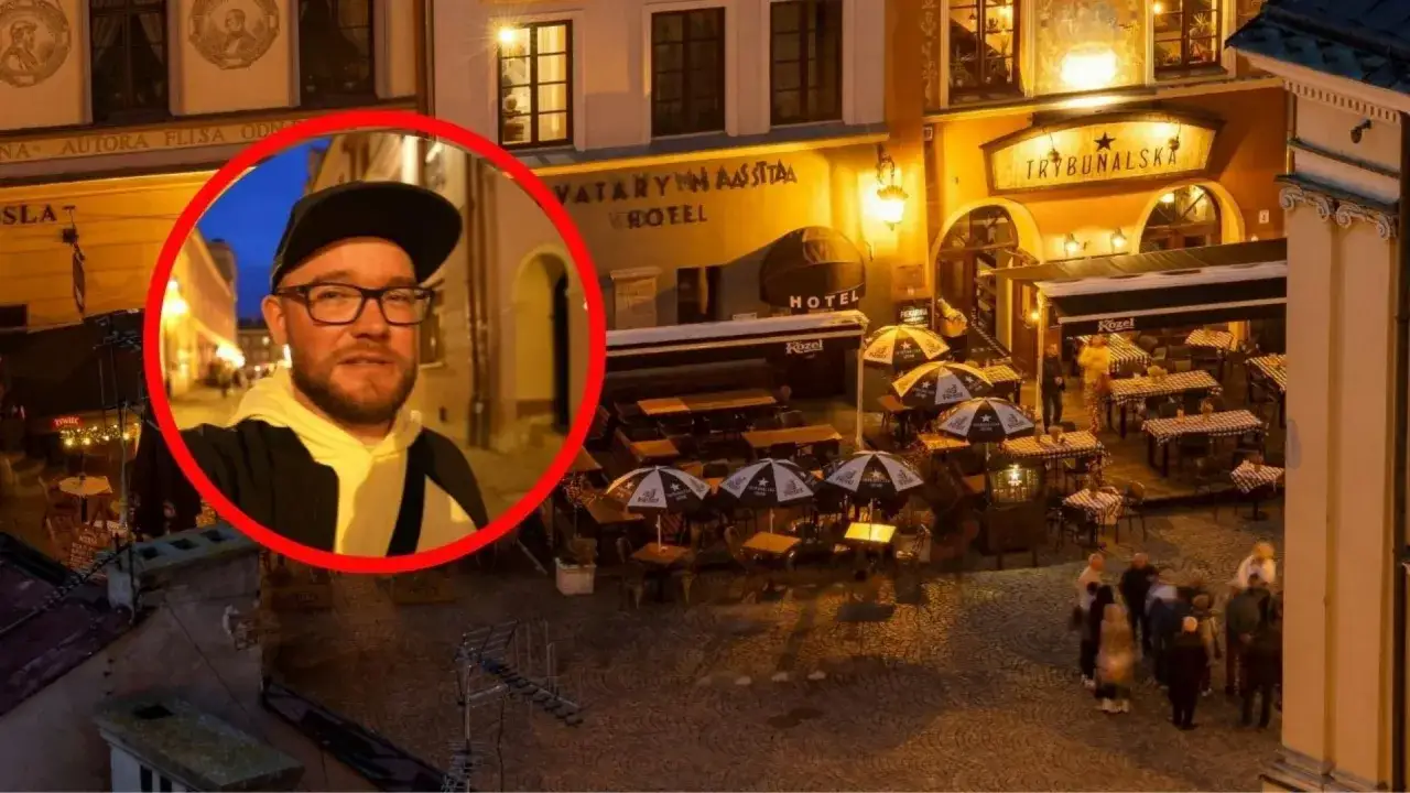 Mężczyzna w okularach i czapce na tle nocnego Lublina. Widać hotel i restaurację 