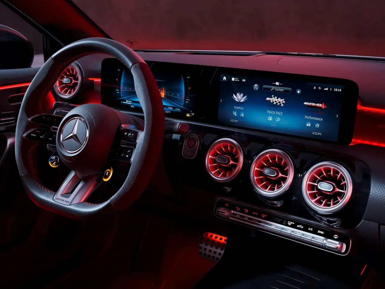 Interni della Mercedes Classe A 2026 con illuminazione rossa, volante AMG, schermi digitali e bocchette d'aria sportive.