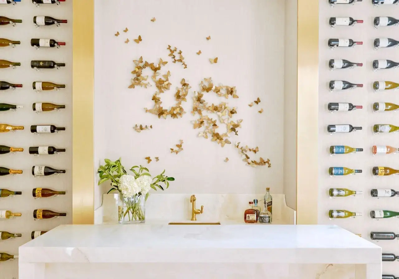 Ein schmetterling muster ziert die Wand über einem goldenen Wasserhahn und einer Marmorbar. Weinregale flankieren die Szene.