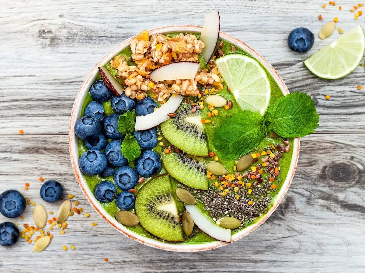 Zielony smoothie bowl z jagodami, kiwi i granolą, przypominający wyglądem tradycyjny kisiel.