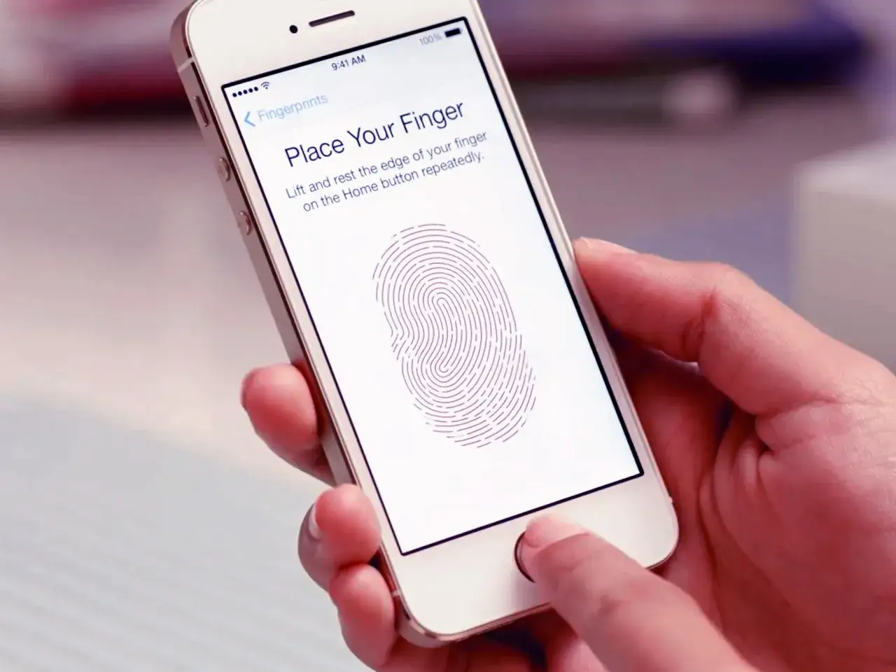 En hand h&aring;ller en iPhone som visar instruktioner f&ouml;r att registrera fingeravtryck med touch ID.